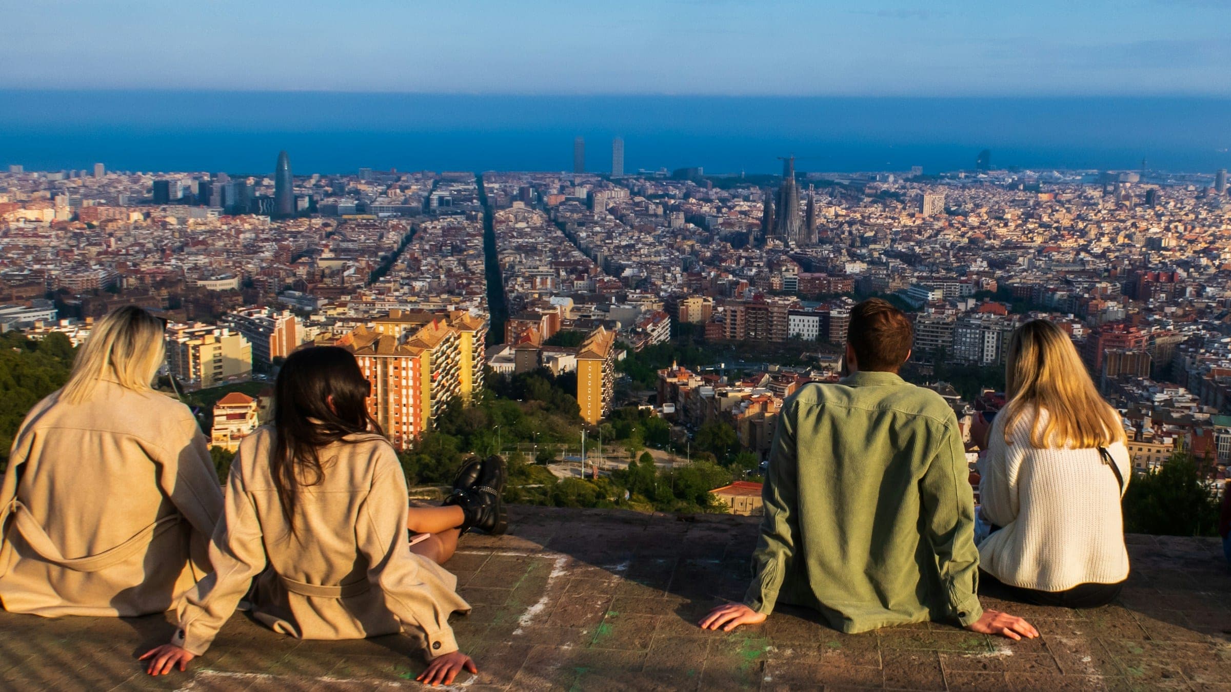 Friends sitting together at a busy public viewpoint above Barcelona in daylight