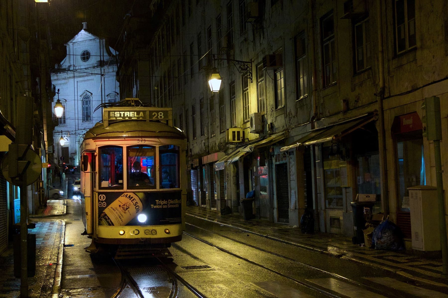 Yellow tram number 28 on a lamp-lit Lisbon street at night