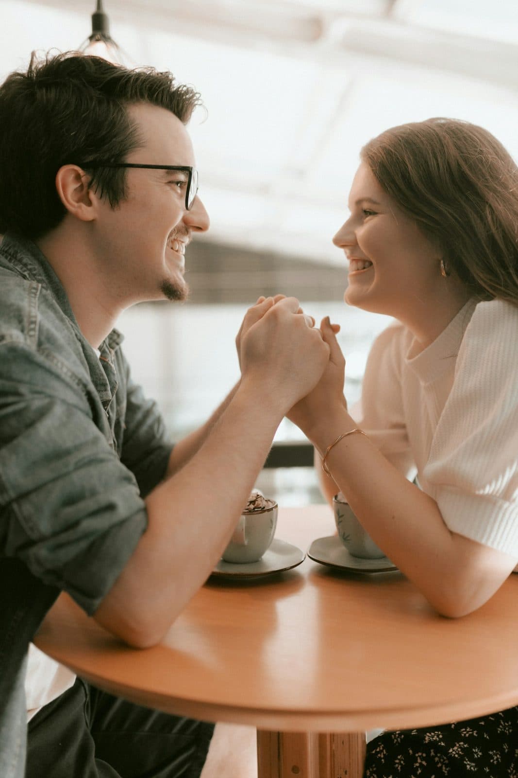 A couple smiling and holding hands over coffee