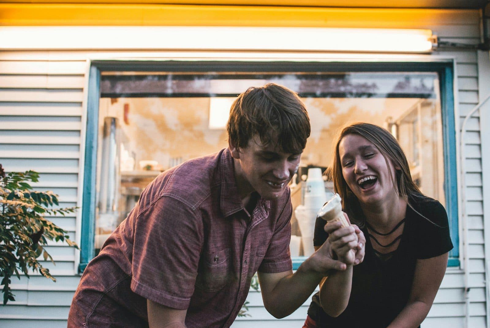 Two travellers laughing over ice cream on a sunny city street