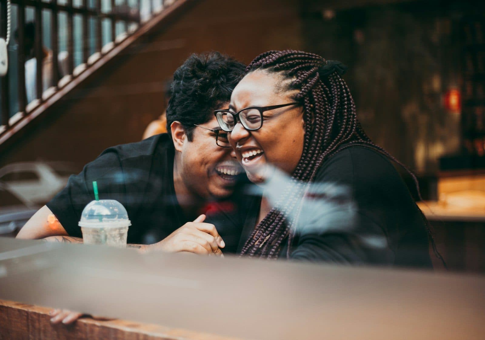 A man and a woman laughing together at a café table on a first date