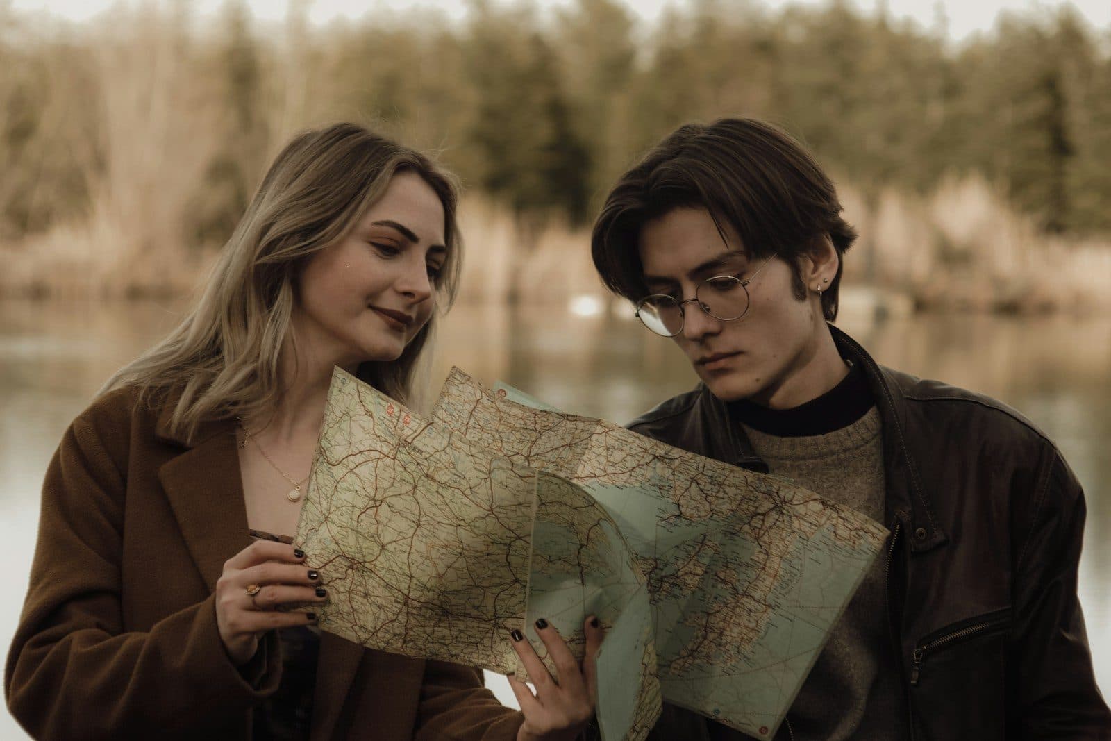 Two travellers reading a paper map together by a lake