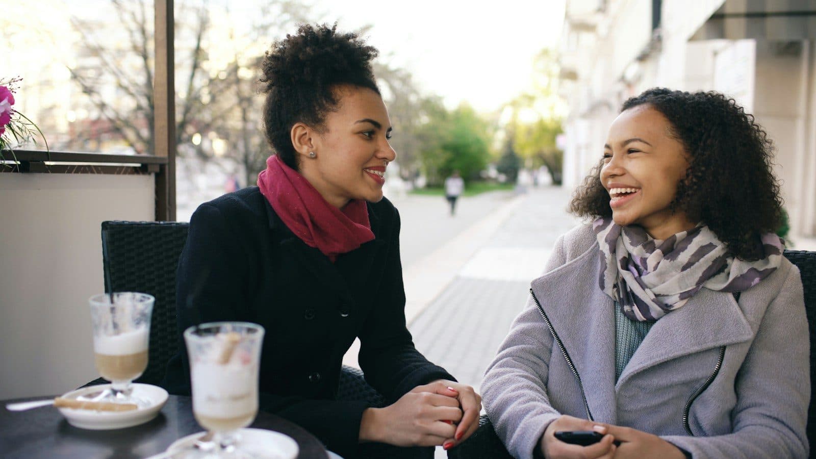 Two friends laughing at an outdoor café in daylight