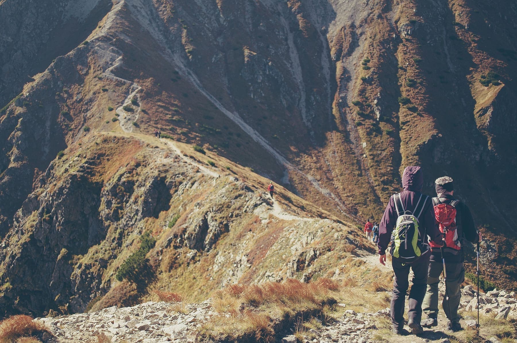 Hikers walking along a steep mountain ridge