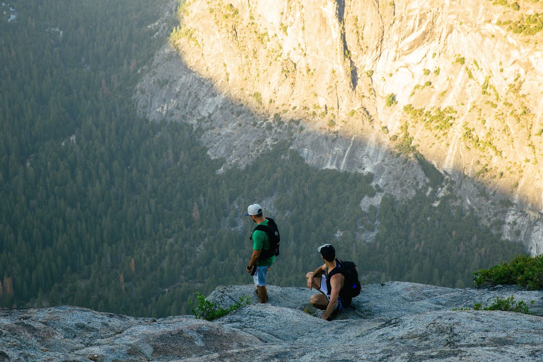 Two hikers resting on a cliff top in the mountains