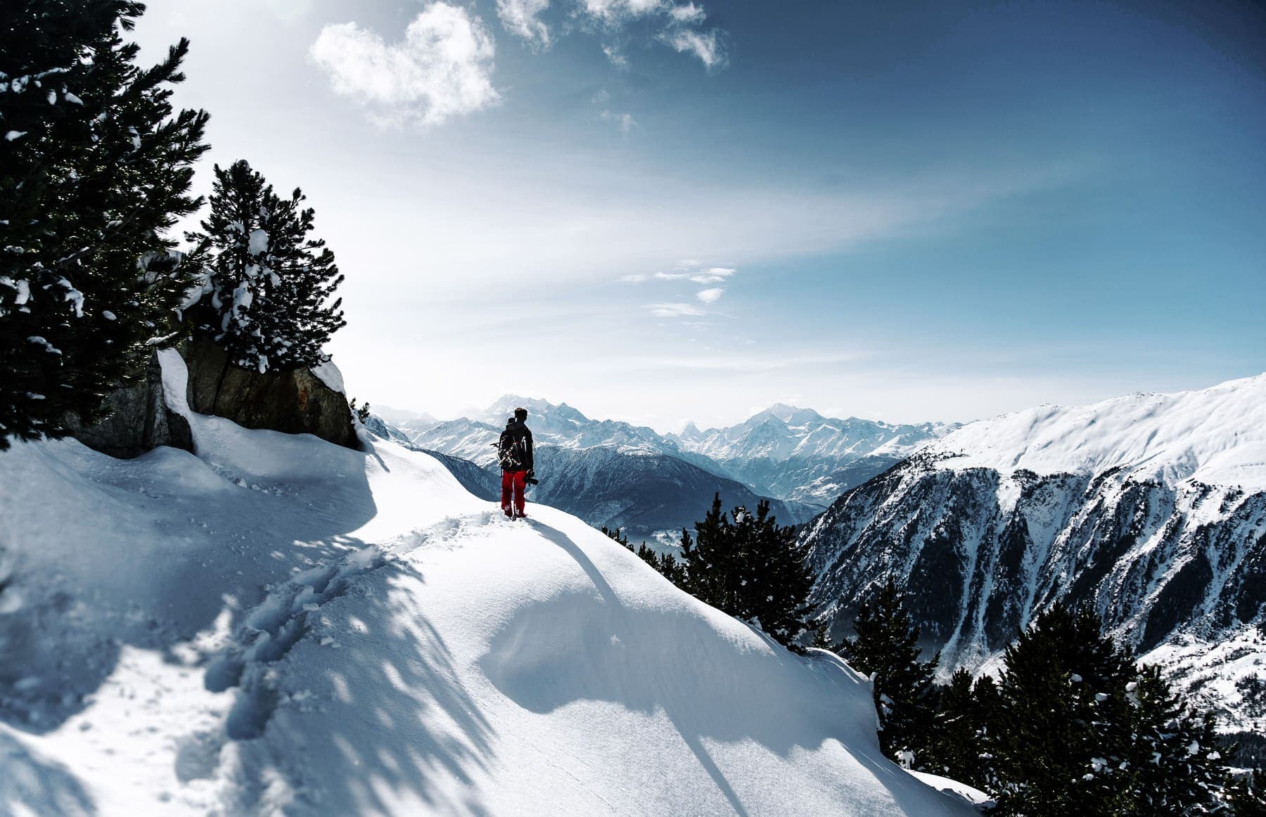 Hiker on a snowy mountain ridge under a blue sky