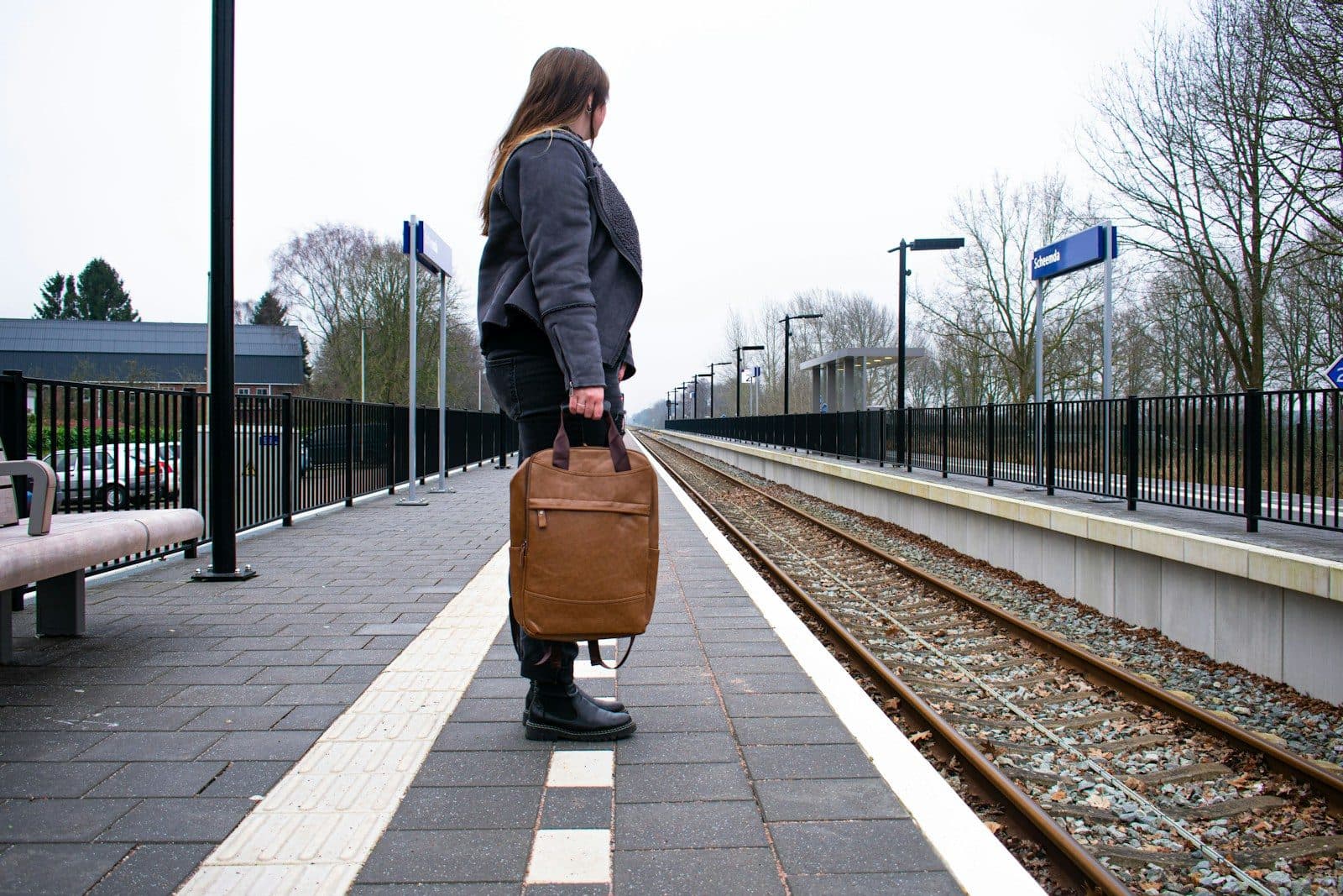 A woman with a travel bag waiting on a railway platform