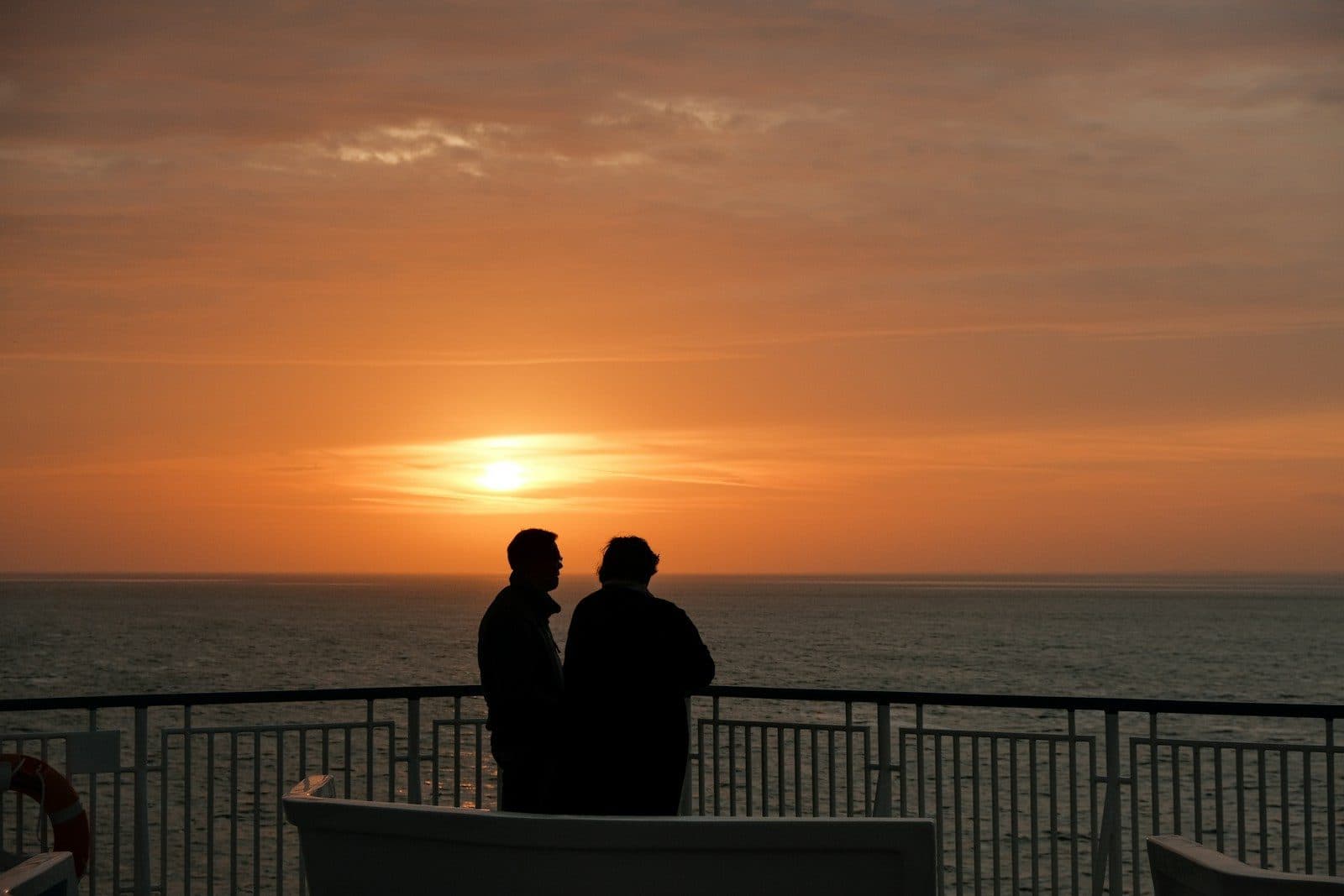 Two travellers watching the sun set over the sea