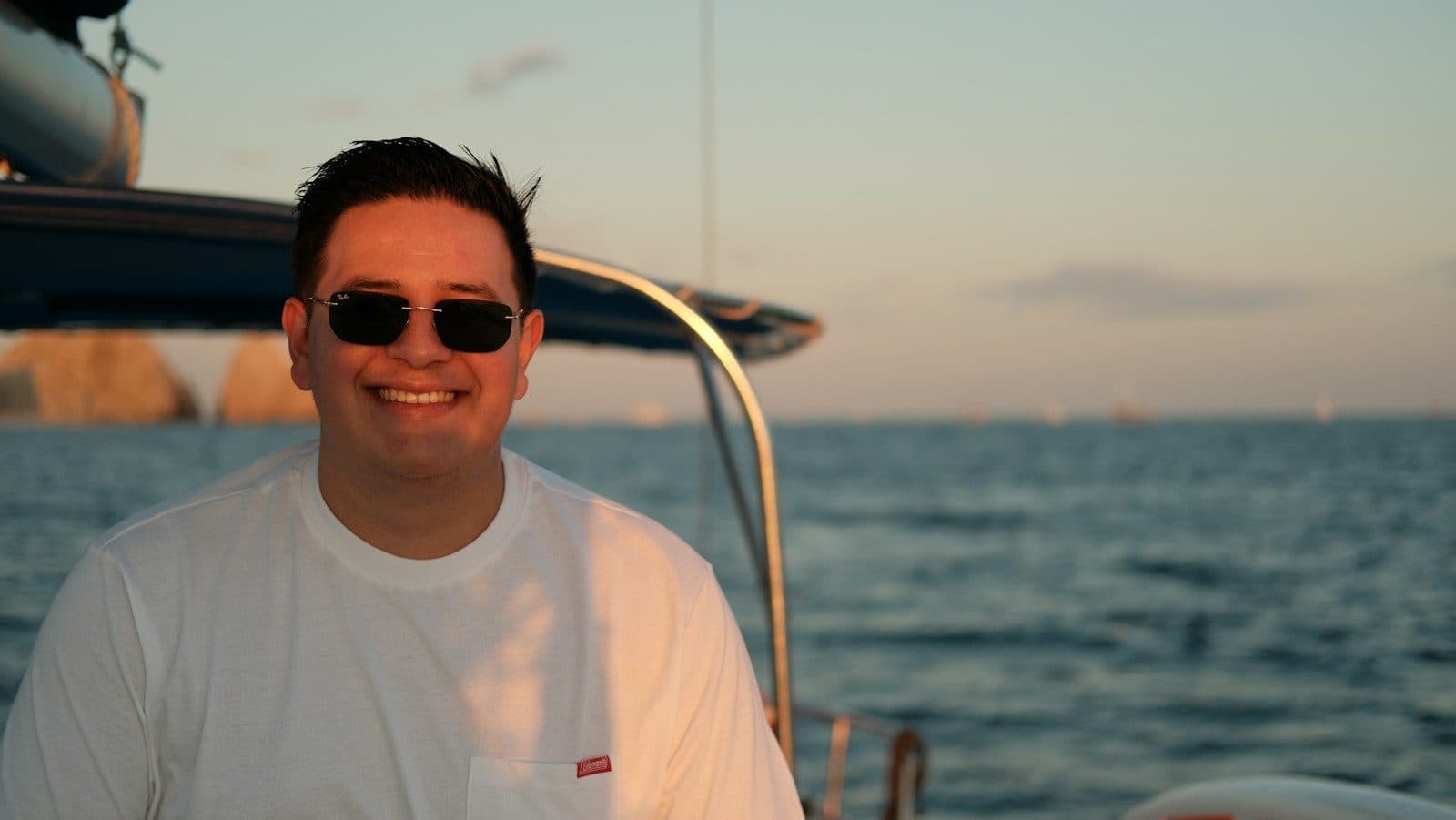 A smiling man on a sailing boat at sunset