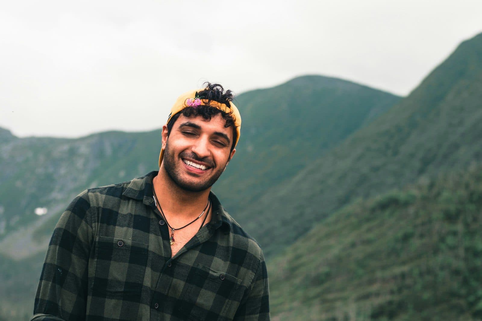 A smiling traveller in front of green mountains